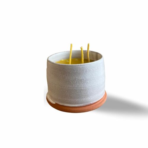 White pottery pot with beeswax candle with three wicks.