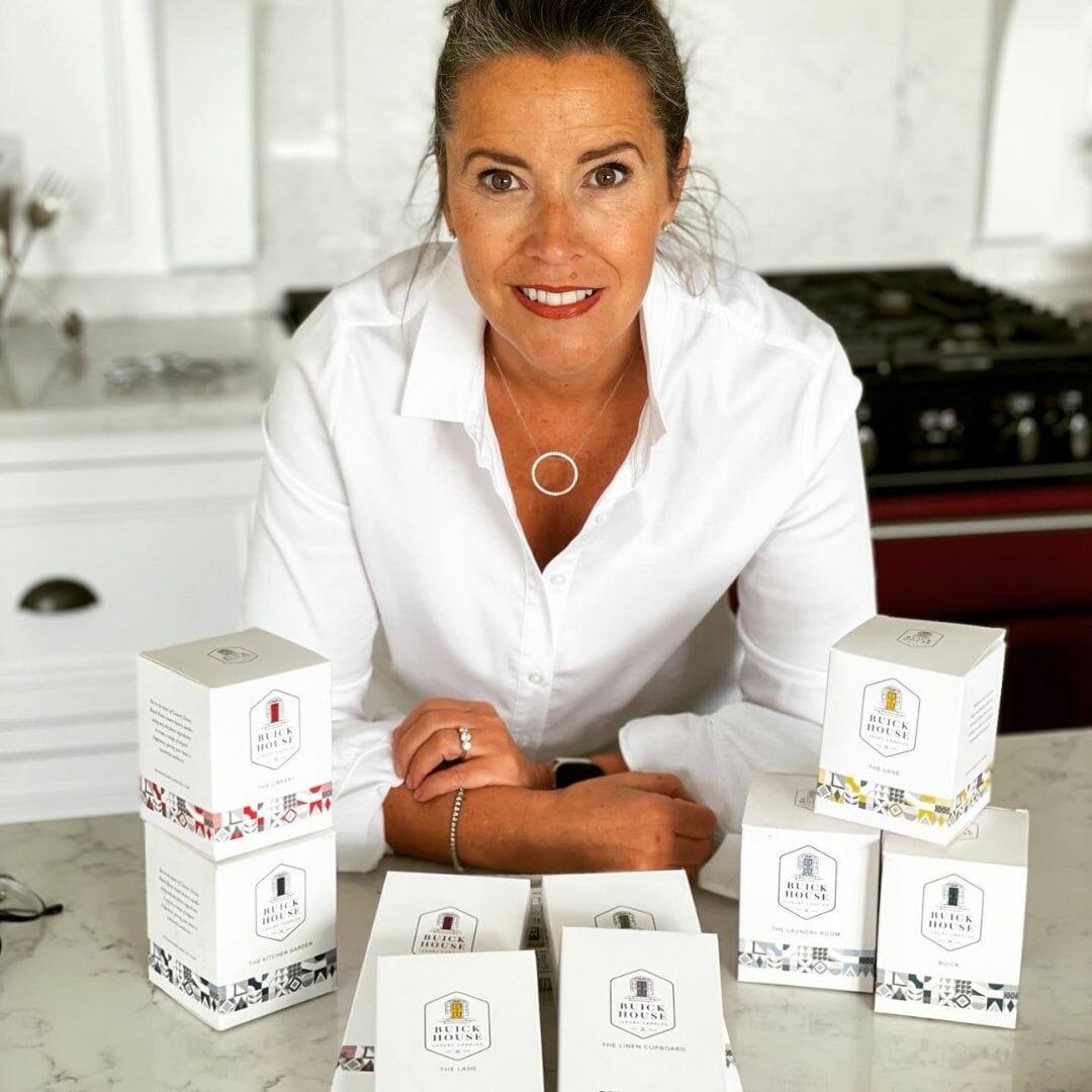 Lady candle maker standing beside candles in boxes