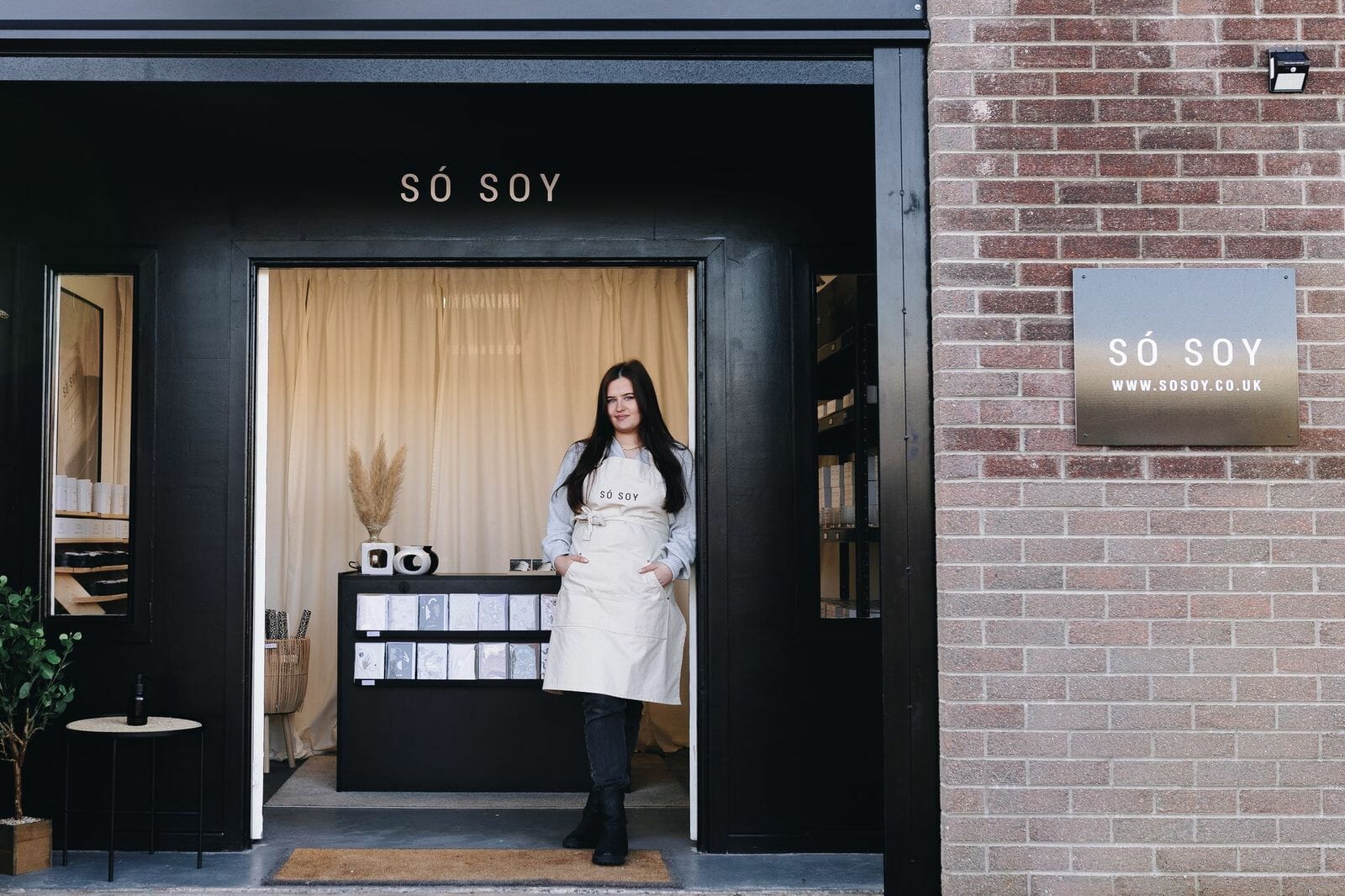 Woman standing at door way of shop called So Soy.
