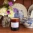 Amber glass candle, called the Atlantic sitting on a shelf beside blue delph.